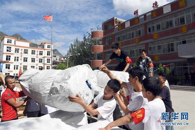 7月16日，在舟曲县南峪乡，志愿者在临时物资转运点搬运救灾物资。 新华社记者 范培珅 摄